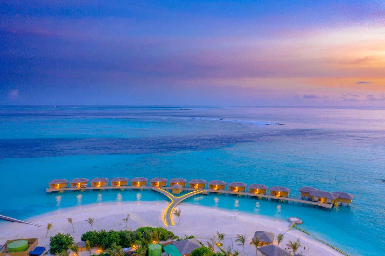A breathtaking aerial shot of overwater bungalows in the Maldives during sunset.